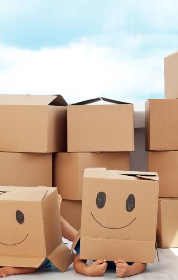 Kids having fun while moving in a new home playing with boxes